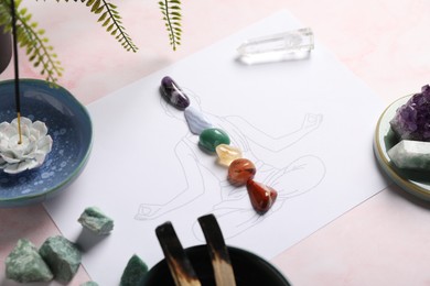 Photo of Human drawing with gemstones placed on chakras, incense and palo santo against light background, closeup