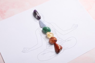 Photo of Human drawing with gemstones placed on chakras against light background, closeup