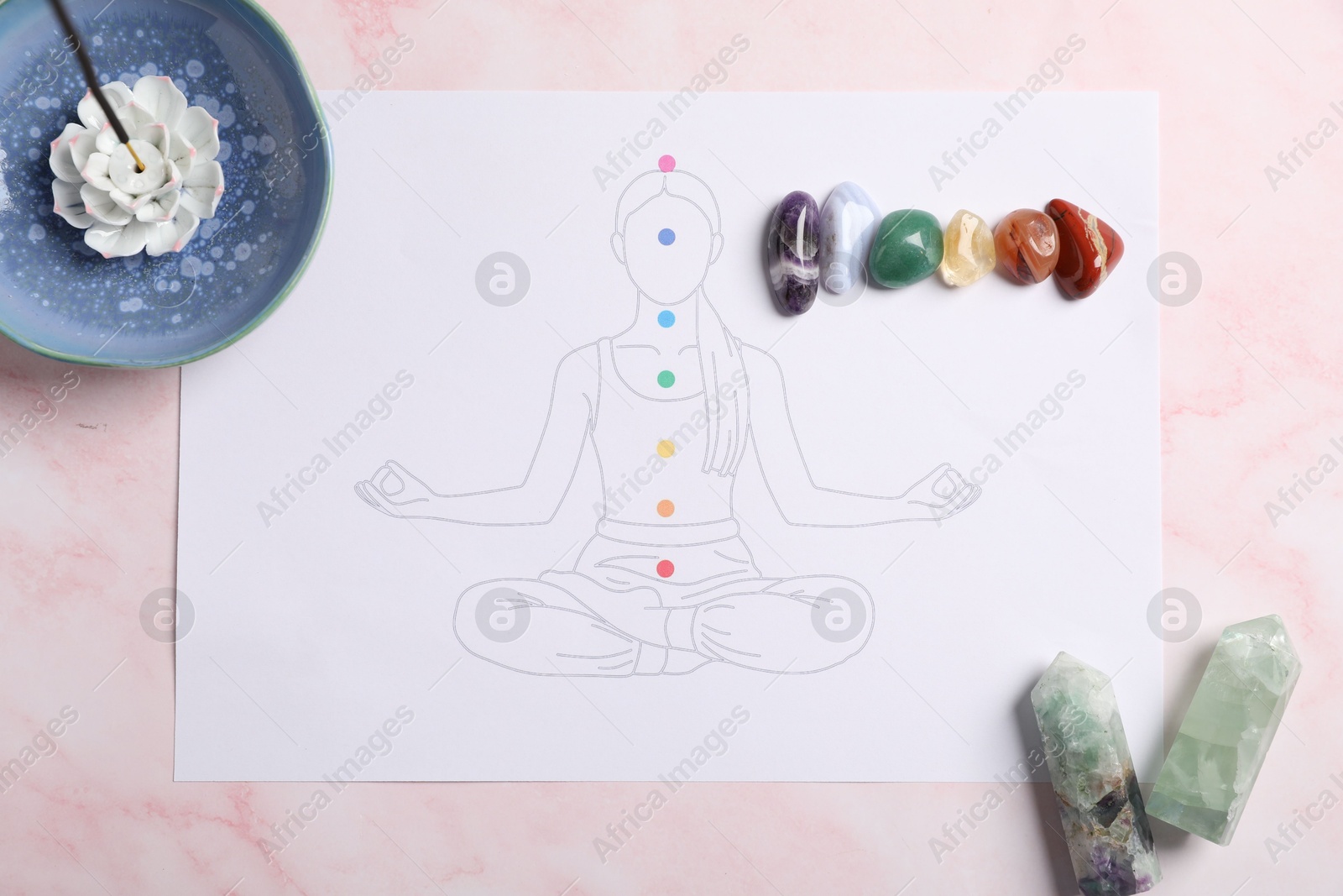 Drawing of chakras on human body, gemstones, incense on light pink table, flat lay Photo of Drawing of chakras on human body, gemstones, incense on light pink table, flat lay