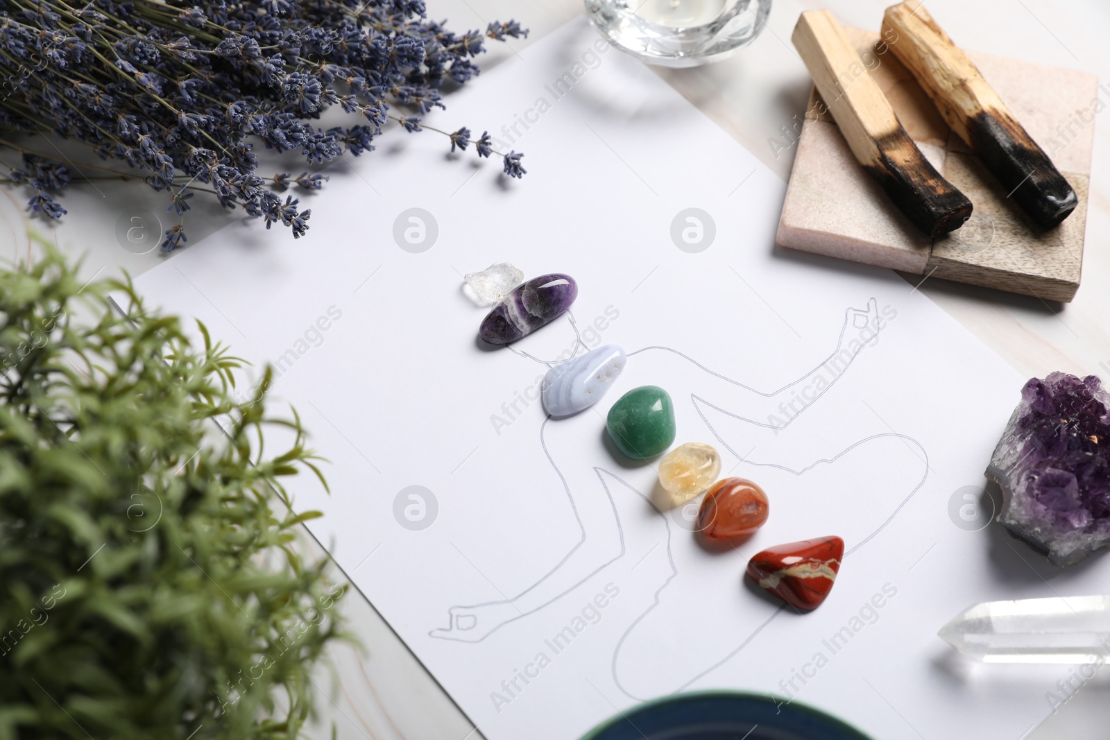 Human drawing with gemstones placed on chakras, plants and palo santo against white background, closeup Photo of Human drawing with gemstones placed on chakras, plants and palo santo against white background, closeup