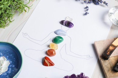 Photo of Human drawing with gemstones placed on chakras, plants and palo santo against white background, closeup