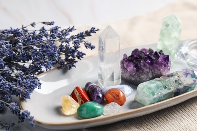 Photo of Different gemstones and lavender flowers on table, closeup