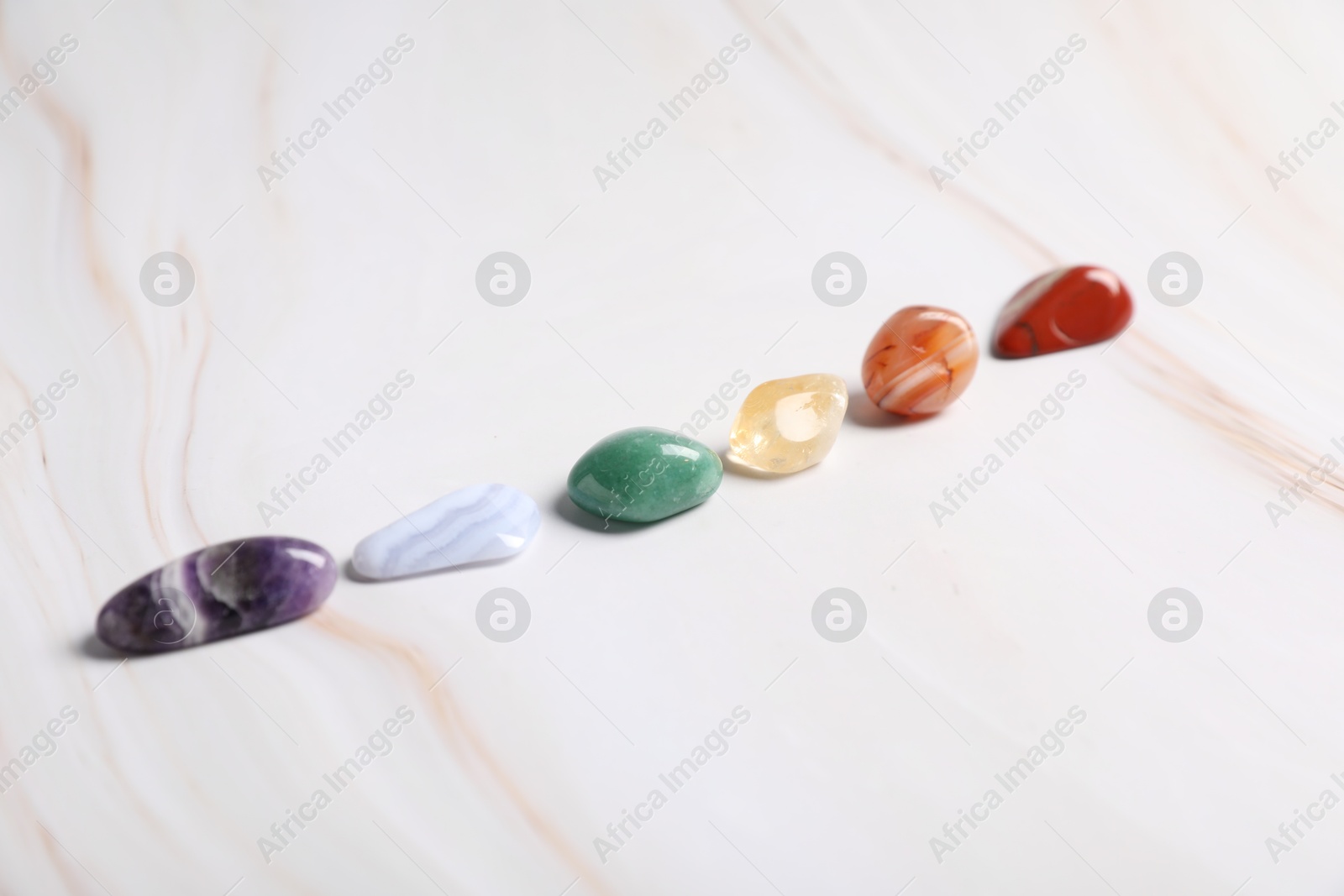 Natural chakra gemstones on white table, closeup Photo of Natural chakra gemstones on white table, closeup