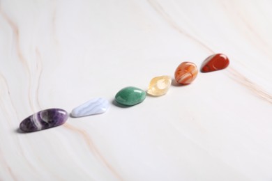 Photo of Natural chakra gemstones on white table, closeup