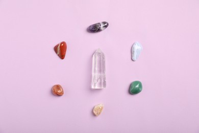 Photo of Seven chakra gemstones on lilac background, flat lay