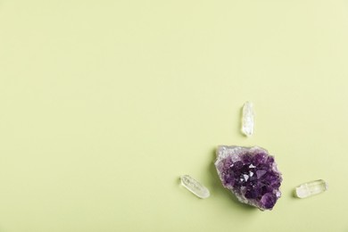 Photo of Different gemstones on light green background, flat lay. Space for text