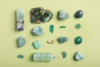 Photo of Different gemstones on light green background, flat lay