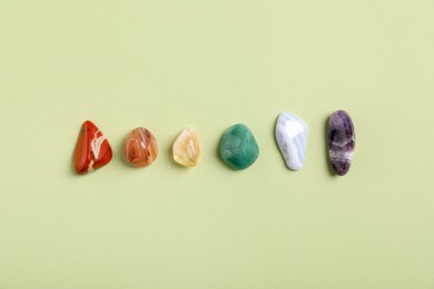 Photo of Chakra gemstones on light green background, flat lay