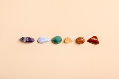 Photo of Chakra gemstones on beige background, flat lay