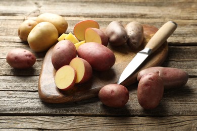 Photo of Different types of potatoes and knife on wooden table, closeup