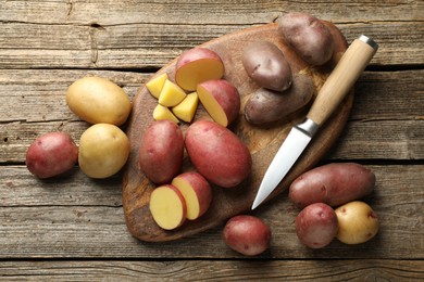 Photo of Different types of potatoes and knife on wooden table, flat lay