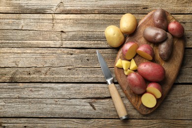 Photo of Different types of potatoes and knife on wooden table, flat lay. Space for text