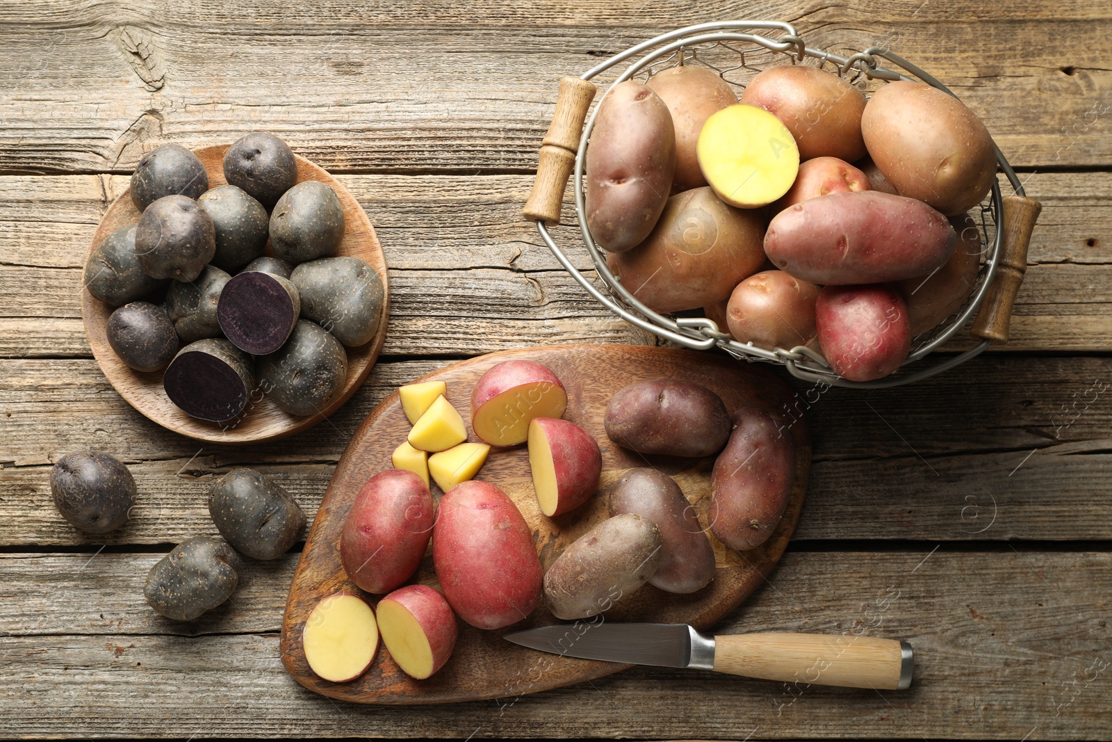 Photo of Different types of potatoes and knife on wooden table, flat lay