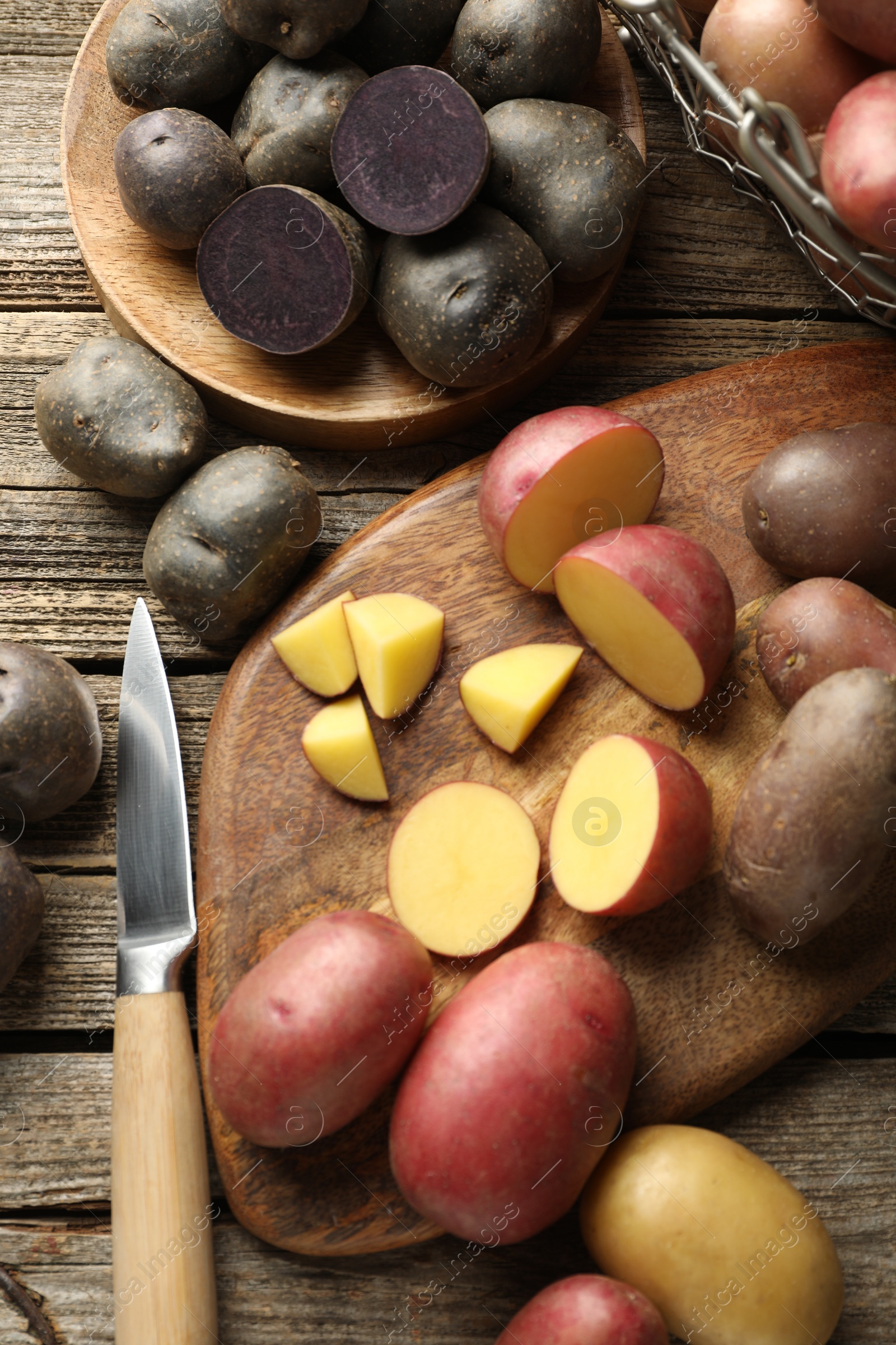 Photo of Different types of potatoes and knife on wooden table, flat lay