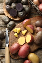 Photo of Different types of potatoes and knife on wooden table, flat lay
