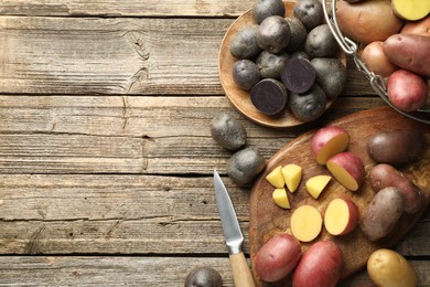 Photo of Different types of potatoes and knife on wooden table, flat lay. Space for text
