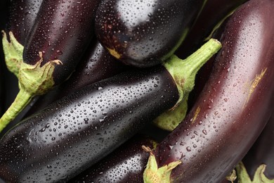 Photo of Many raw ripe eggplants with water drops as background, top view