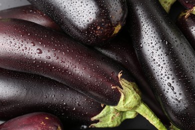 Photo of Many raw ripe eggplants with water drops as background, top view