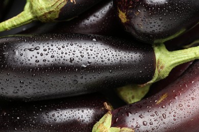 Photo of Many raw ripe eggplants with water drops as background, top view