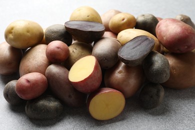 Photo of Different types of potatoes on grey table, closeup