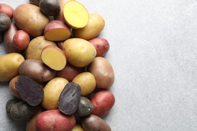 Photo of Different types of potatoes on grey table, flat lay. Space for text