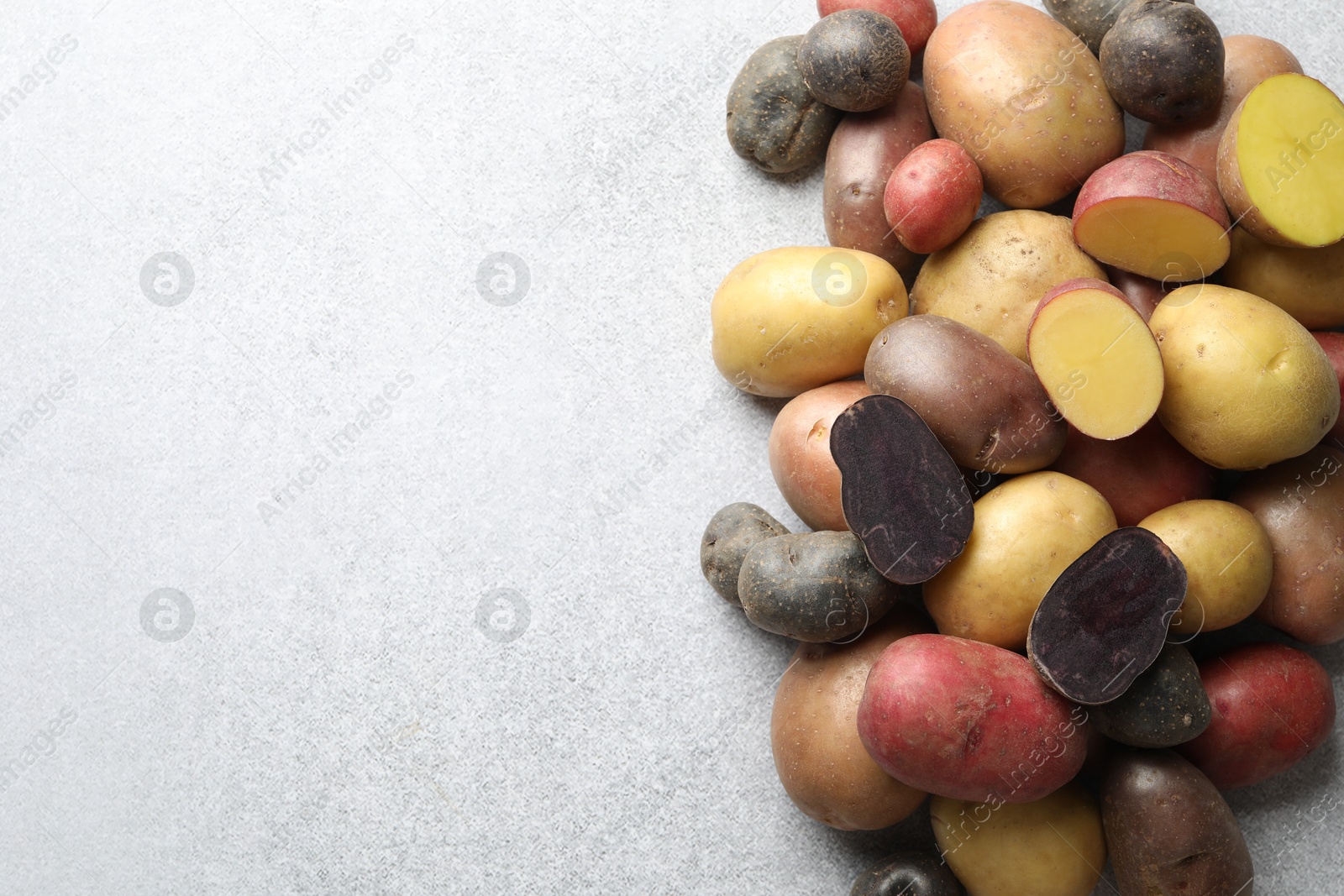 Photo of Different types of potatoes on grey table, flat lay. Space for text