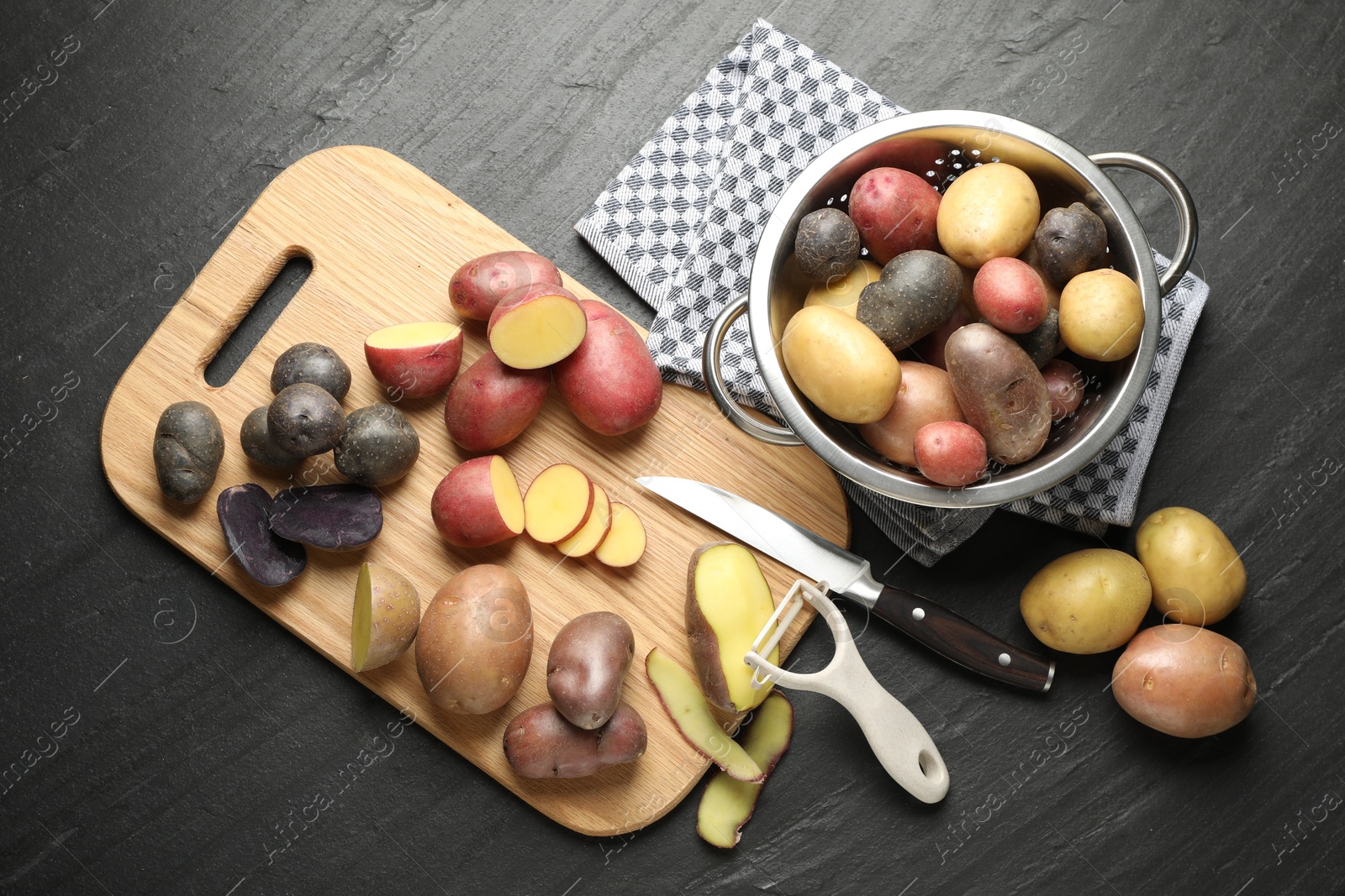 Photo of Different types of potatoes, peeler and knife on black table, flat lay