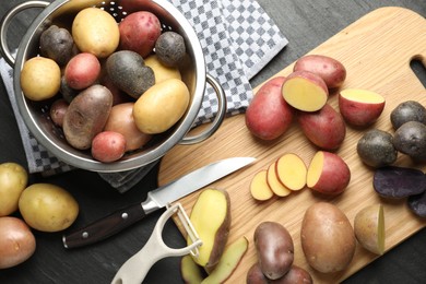 Photo of Different types of potatoes, peeler and knife on black table, flat lay