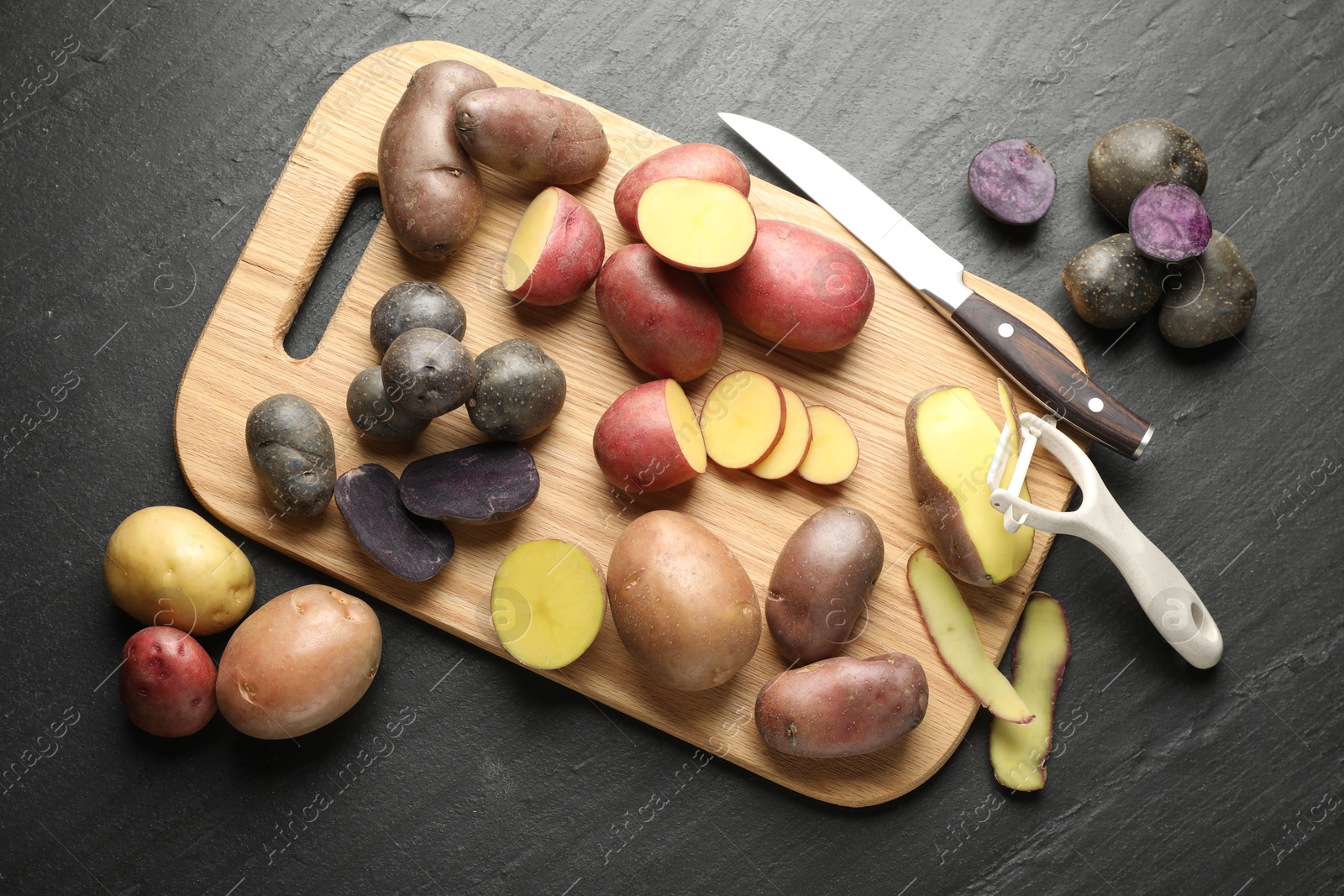 Different types of potatoes, peeler and knife on black table, flat lay Photo of Different types of potatoes, peeler and knife on black table, flat lay