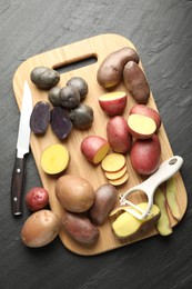 Photo of Different types of potatoes, peeler and knife on black table, flat lay