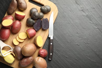 Photo of Different types of potatoes, peeler and knife on black table, flat lay. Space for text