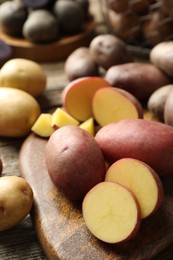 Photo of Different types of potatoes on wooden table, closeup