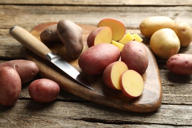 Photo of Different types of potatoes and knife on wooden table, closeup