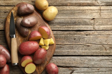 Photo of Different types of potatoes and knife on wooden table, flat lay. Space for text