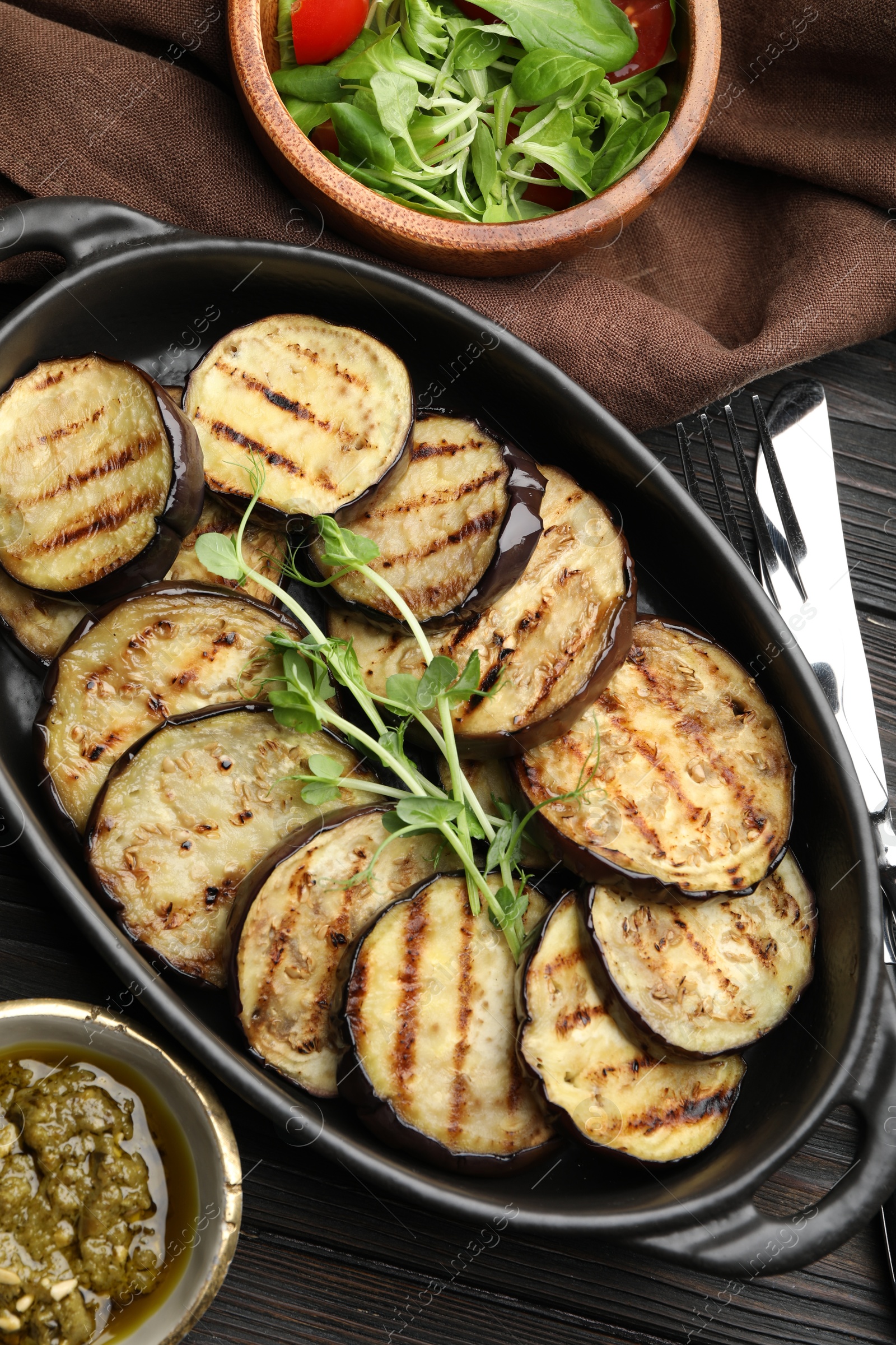 Photo of Grilled slices of eggplant with microgreens served on wooden table, flat lay