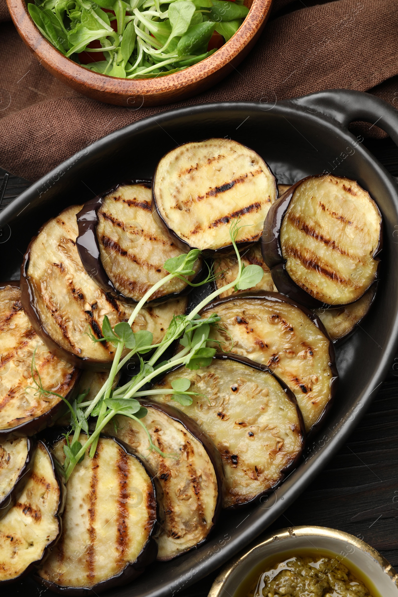 Photo of Grilled slices of eggplant with microgreens served on wooden table, flat lay