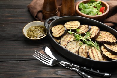 Photo of Grilled slices of eggplant with microgreens served on wooden table, closeup