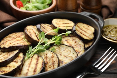 Photo of Grilled slices of eggplant with microgreens served on wooden table, closeup