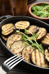 Photo of Grilled slices of eggplant with microgreens served on wooden table, closeup