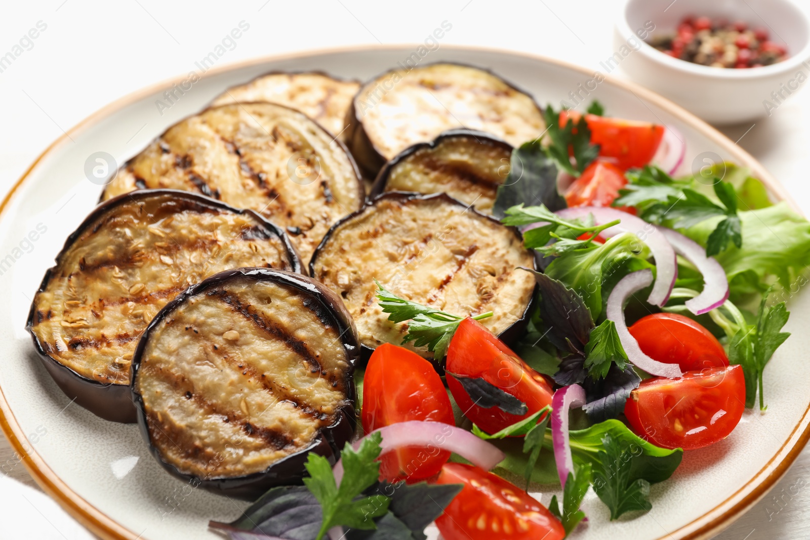 Photo of Grilled slices of eggplant with salad on white table, closeup