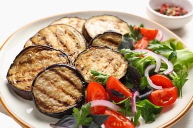 Photo of Grilled slices of eggplant with salad on white table, closeup