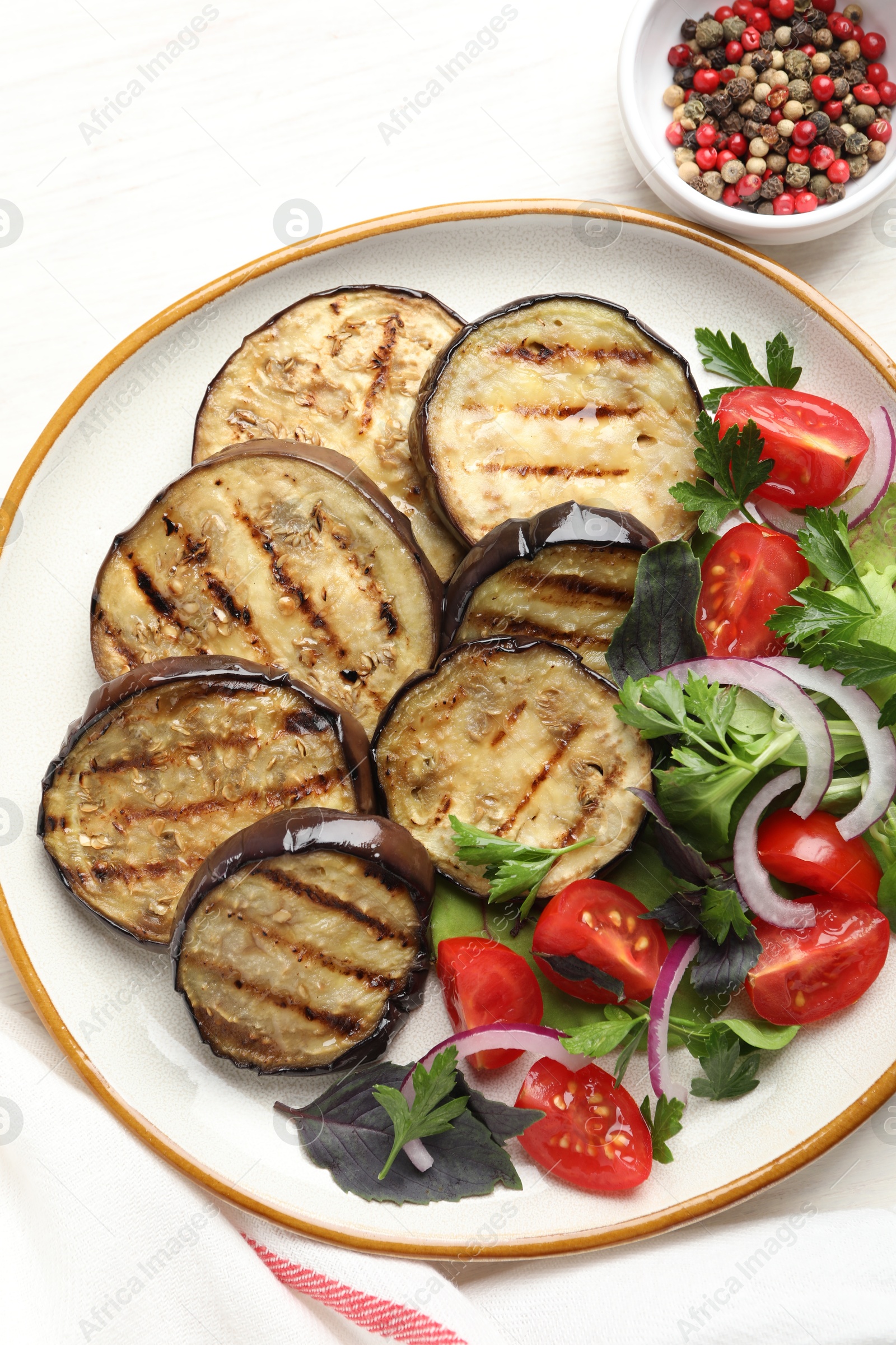 Photo of Grilled slices of eggplant with salad and peppercorns on white table, top view