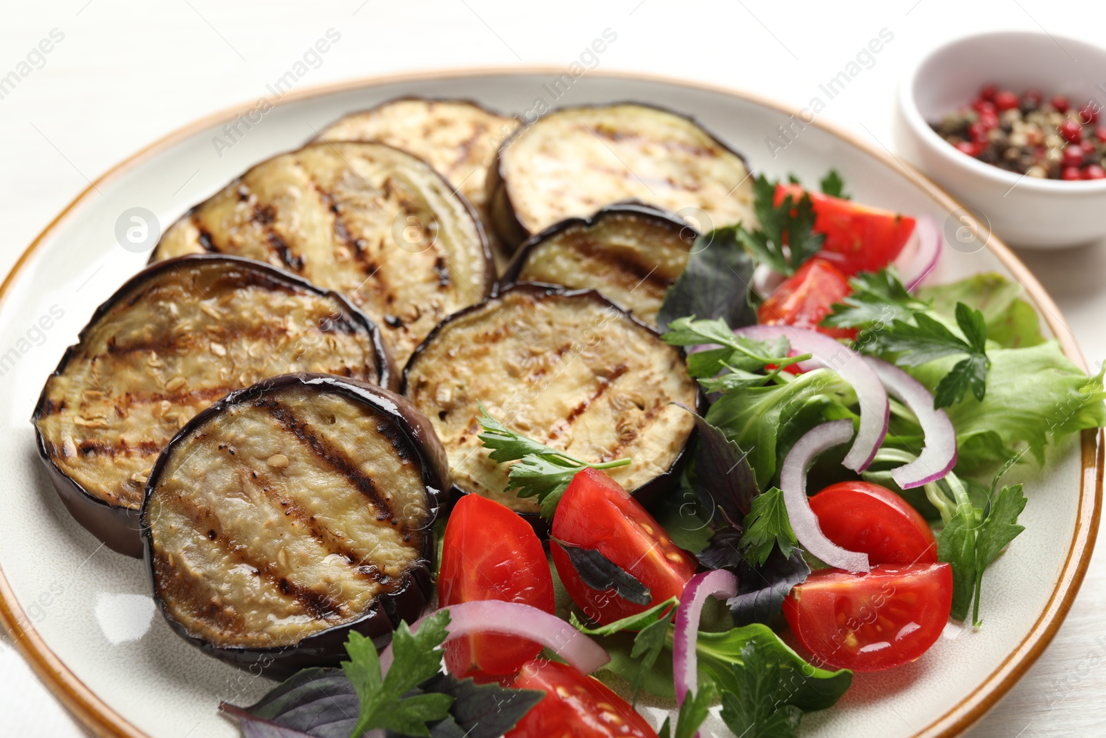 Grilled slices of eggplant with salad on white table, closeup Photo of Grilled slices of eggplant with salad on white table, closeup