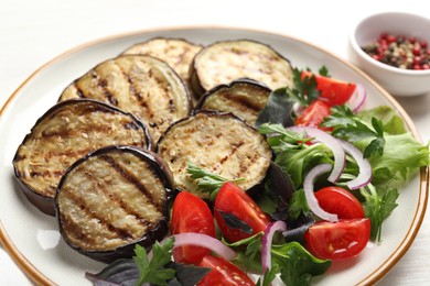 Photo of Grilled slices of eggplant with salad on white table, closeup