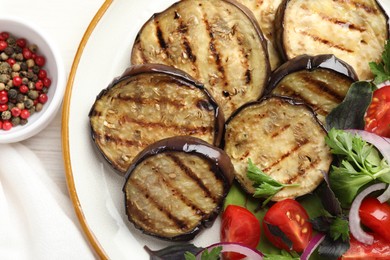 Photo of Grilled slices of eggplant with salad and peppercorns on white wooden table, top view