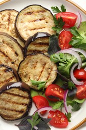 Photo of Grilled slices of eggplant with salad on white table, closeup