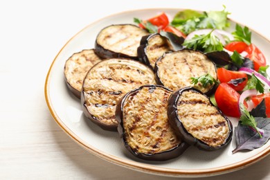 Photo of Grilled slices of eggplant with salad on white table, closeup