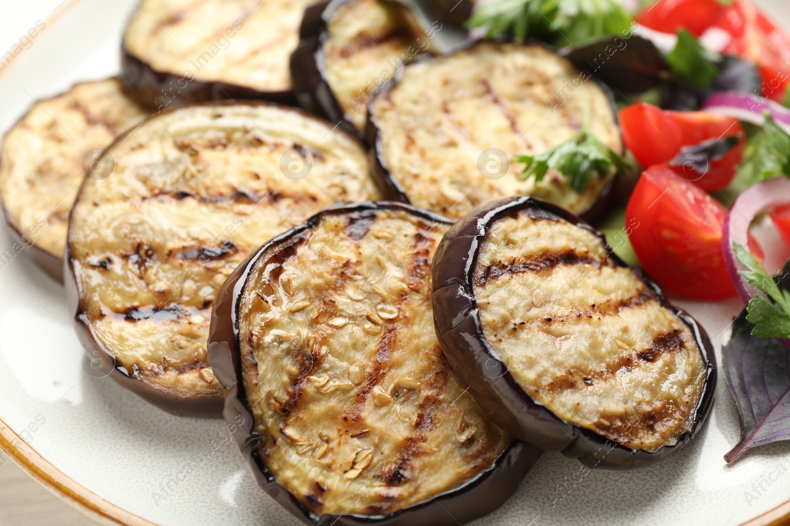 Grilled slices of eggplant with salad on white table, closeup Photo of Grilled slices of eggplant with salad on white table, closeup