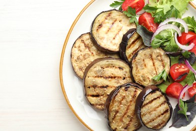 Photo of Grilled slices of eggplant with salad on white wooden table, top view. Space for text