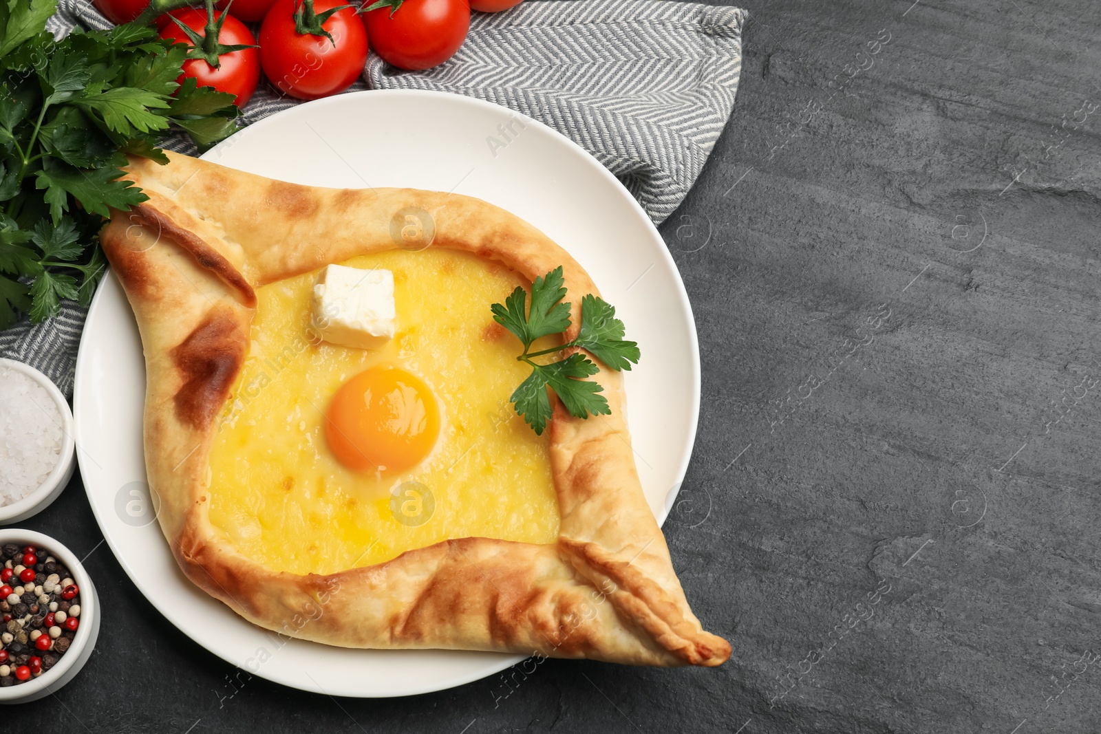 Photo of Tasty khachapuri with cheese, egg and other products on black table, flat lay. Space for text